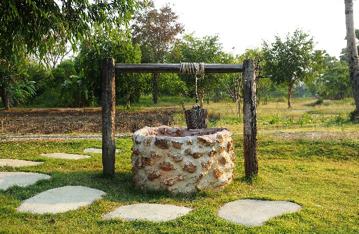 Altertümlicher Schachtbrunnen mit Eimer in Garten.
